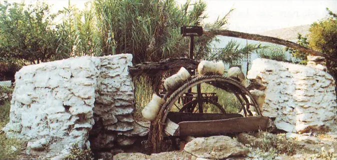 ancient water wheel with stone structures surrounded by provista grass turf and vegetation