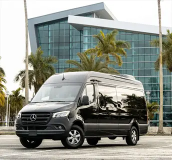 black mercedes-benz sprinter van parked near modern glass building with palm trees