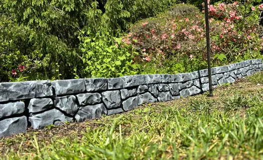 compact shrub garden border with stone edging and flowering bushes in background