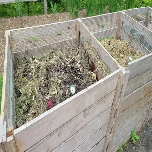 compost tumbler garden with wooden bins filled with organic matter and greenery background