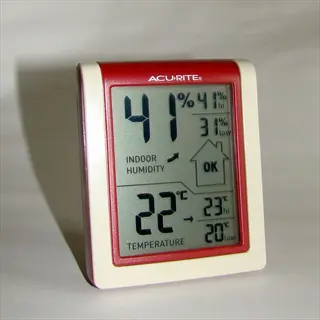 digital thermometer hygrometer (acurite brand) displaying 22°c temperature and 41% humidity on lcd screen with status indicators, against light gray background