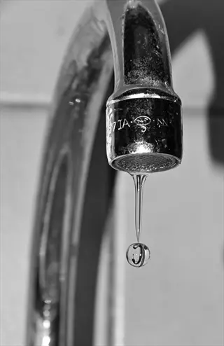 faucet aerator installation sink: close-up of a dripping kitchen faucet with visible aerator, demonstrating water-efficient fixture upgrades