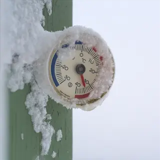 frost-covered garden thermometer showing cold weather conditions