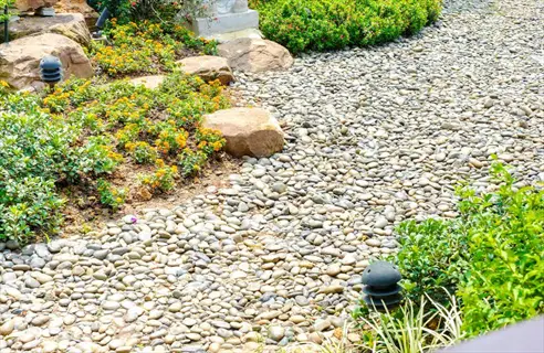 gravel pathway landscaping with decorative rocks, flowering shrubs, and garden lighting