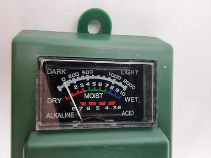 green plant light meter device with analog dial showing light (dark to light) and moisture (dry to wet) measurement scales