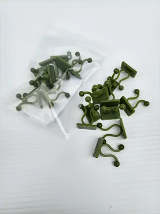green plastic grow light clips with round heads and curved arms, displayed in and outside a clear bag on white surface