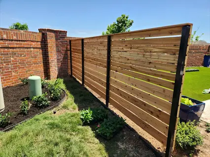 hog panel garden fence with horizontal wood slats and metal posts beside a brick wall and garden greenery
