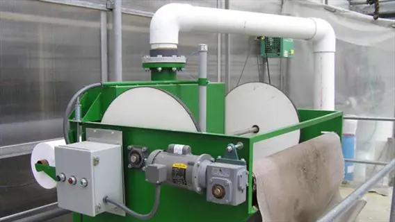 industrial greenhouse water filtration system featuring a large green treatment unit with cylindrical components, control panel, and white pvc piping for water processing