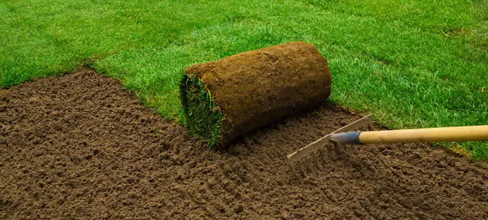 installation of rolled sports field turf on prepared soil with rake