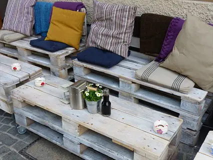 pallet garden furniture including sofas with cushions and a table with decorative items in an outdoor space