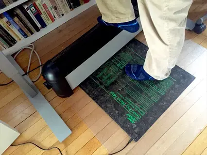 person standing on seedling heat mat for temperature regulation in indoor garden setup with bookshelf background