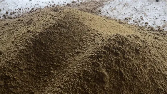 pile of bone meal powder showing textured, grainy brown surface with natural height variation and scattered particles