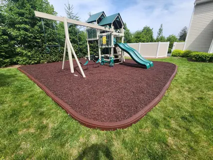 playground with wood chip playground surface, swings, dual slides, and climbing structure on sunny day
