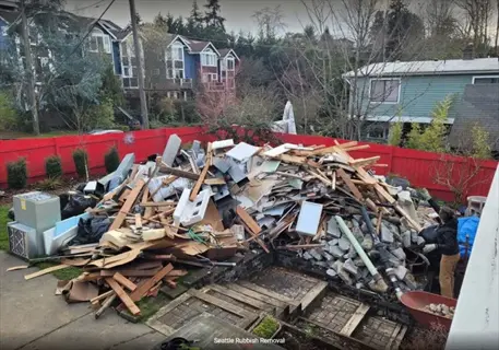 residential backyard garden debris cleanup pile with wood, appliances, and a worker - seattle rubbish removal service text visible