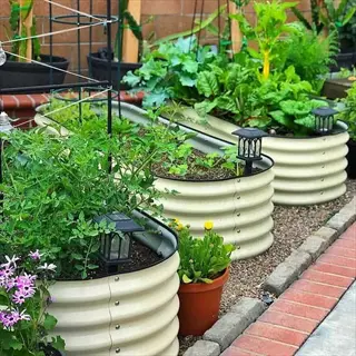 row of metal raised garden beds with corrugated sides, growing vegetables and herbs, with solar lights and brick edging