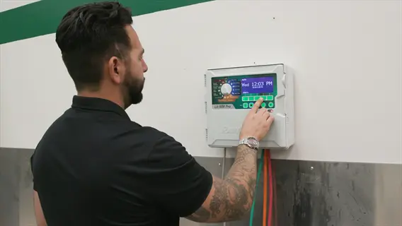 smart sprinkler controller garden: person configuring a wall-mounted irrigation control panel with digital display and colored wires