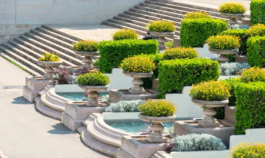 terrace water fountain garden with tiered planters, yellow flowers, and water features