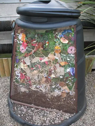 transparent-panel balcony compost bin showing layered organic waste like food scraps and shredded paper