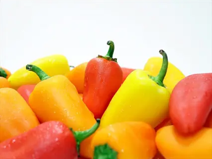 vibrant colorful ripe peppers (red, yellow, orange) with water droplets on white background