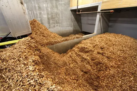 wood chip biomass facility storage area with large piles of processed wood chips