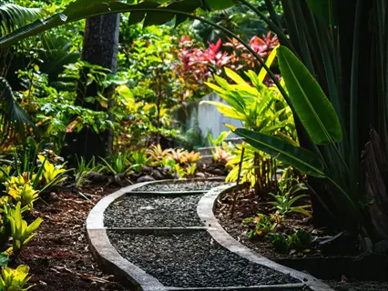 wood chip garden pathway bordered by concrete edging, winding through lush tropical greenery and vibrant plants