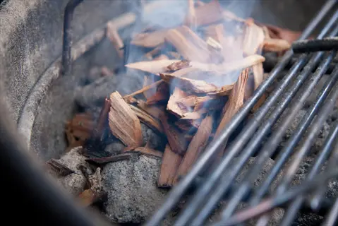 wood chips smoking in a grill/smoker setup, prepared for meat smoking process